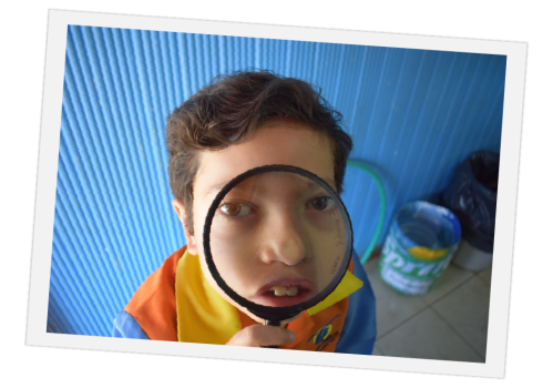 Niño mira la cámara a través de una lupa escolar